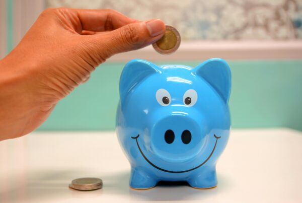 hand putting money in blue piggy bank