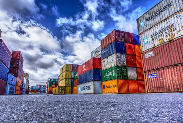 Stacked freight containers in a port warehouse, symbolising customs clearance and imports from third countries.